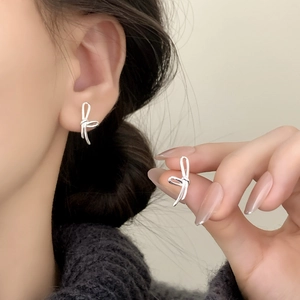 Minimalist silver bow earrings for women featuring sleek ribbon design on model