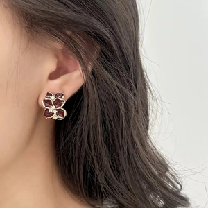Close-up of elegant dark red enamel flower earring with white diamond center on ear