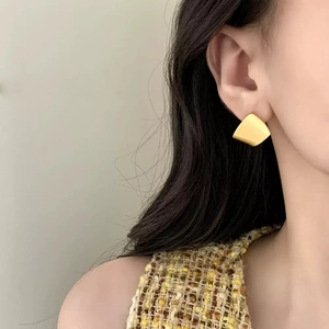 Minimalist matte gold geometric earrings worn by model showing elegant brushed texture