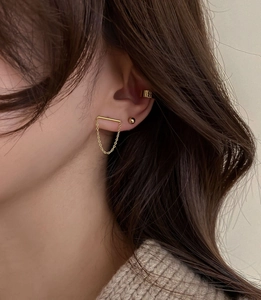 Detail of gold chain drop earring, round stud, and textured ear cuff set on model