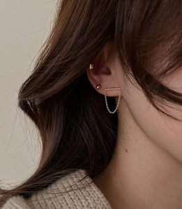 Detailed view of minimalist gold chain earrings and ear cuff on model's ear