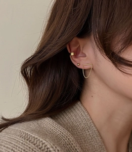 Close-up of a 3-piece gold chain earring set with cuff and stud on a model ear