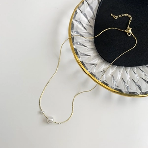 Minimalist gold necklace with dual white pearls on a fine chain and adjustable clasp