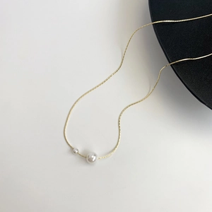 Elegant gold pearl necklace with double white beads on a minimalist background