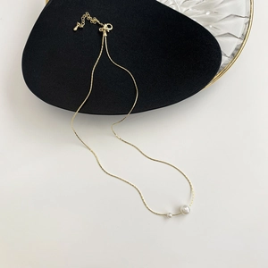 Detail of minimalist gold-plated snake chain necklace with double white pearls