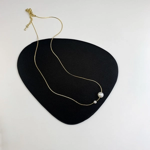 Detail of minimalist gold double pearl necklace showing adjustable lobster clasp and chain