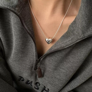 Dettaglio di una collana con ciondolo a cuore argento su catena a serpente indossata