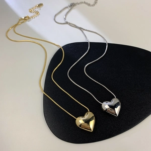Dettaglio di grandi ciondoli a cuore in oro e argento su catene a serpente
