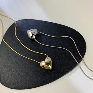 Dettaglio dei ciondoli a cuore 3D in oro e argento con eleganti catene a serpente
