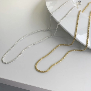 Close-up of elegant gold and silver chain necklace set with shimmering textures on a plate