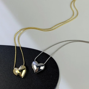 Dettaglio dei ciondoli a cuore in oro e argento su eleganti catene a serpente