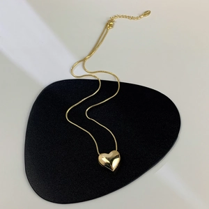 Dettaglio macro della collana con pendente a cuore placcato oro su base in pelle nera