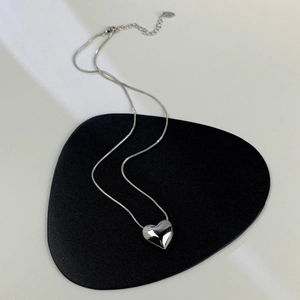 Vista dettagliata del ciondolo a cuore 3D con catena a serpente su supporto in pelle nera