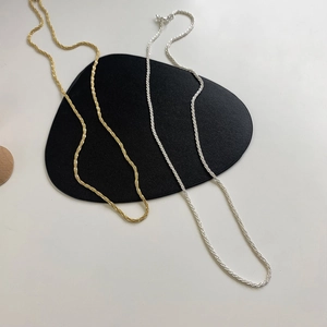 Detail of twisted rope chain necklaces in gold and silver finishes on black leather