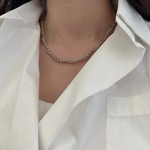 Detail of silver double-layer necklace with snake chain and bead accents on a model