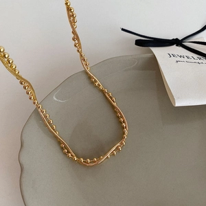 Detail of elegant gold double-layered necklace featuring beaded and snake chains