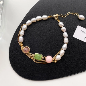 Elegant freshwater pearl bracelet with gold chain and colorful gemstones on black leather