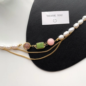 Detail of freshwater pearl necklace with mixed beads and gold chain on leather background
