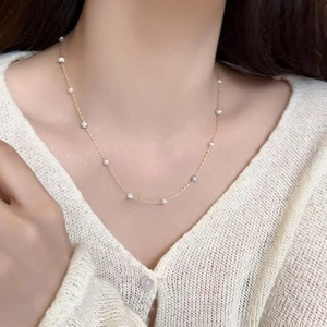 Détail d'un collier en or délicat avec perles blanches sur le cou d'un mannequin