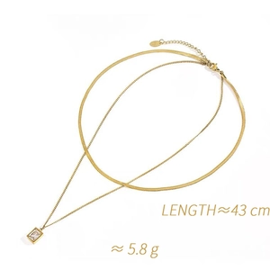 Detailed view of layered gold necklace with flat snake chain and emerald-cut zircon pendant