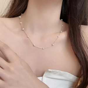 Détail d'un collier chaîne dorée avec perles rondes et billes argentées facettées au cou
