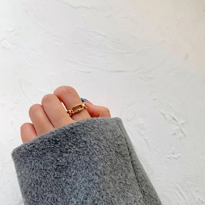 Detail of a double-layered gold chain ring with twisted texture on a model's finger