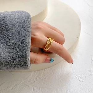 Detail of a double-layered gold twisted rope ring on a model's finger with clean aesthetics