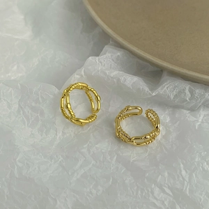 Detail of gold plated twisted double-layer rings with irregular texture on white paper