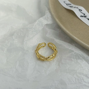 Detail of gold double-layer twisted rope ring with adjustable open band on white paper