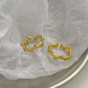 Minimalist double-layered gold wave rings set on a white textured background