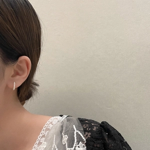 Primo piano di piccoli orecchini a cerchio con perle barocche indossati da una modella