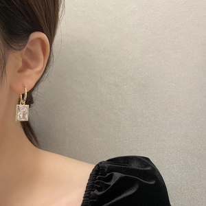 Detailsicht auf elegante goldene Kreisoherringe mit rechteckigem Kristallanhänger