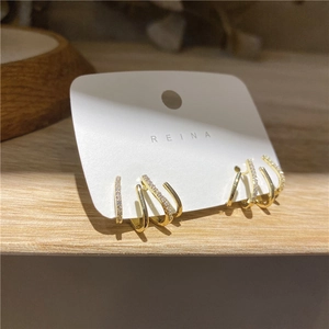Detail of minimalist gold four-claw hook earrings with shimmering micro-paved zircons