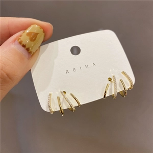 Macro view of four-claw gold earrings with micro-inlaid zircons on a white display card
