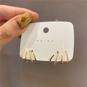Detail of four-claw gold-plated earrings featuring micro-set zircon on parallel metal bands