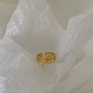 Detailed view of gold nail-shaped ring with pavé cubic zirconia on white background