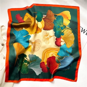 Close-up of colorful ginkgo leaf print silk scarf with bright orange stitched edges