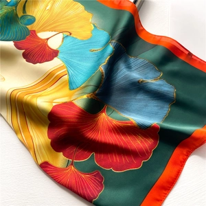 Elegant ginkgo leaf silk scarf with vibrant red and yellow patterns on white background