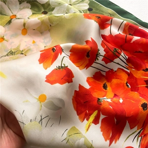 Detailed macro view of silk scarf with vibrant red poppies and white daisy floral pattern