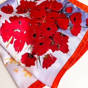 Detail of floral silk scarf showing red poppy print and smooth satin texture finish