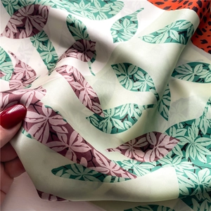 Detailed view of silk-like scarf featuring elegant leaf patterns and leopard prints