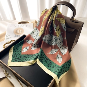 Elegant silk scarf with leopard print and floral patterns draped over a brown leather bag