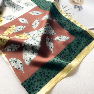 Detail of silk square scarf featuring leaf and leopard prints with elegant rolled edges