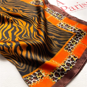Detail of silk scarf with orange and black leopard print and gold chain patterns