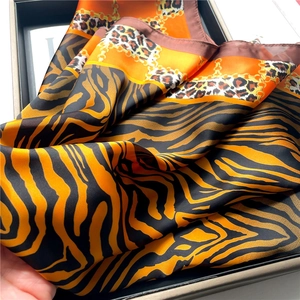 Detailed view of silk leopard print scarf with chain patterns and golden textures