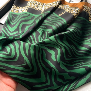 Close-up of leopard and zebra print silk scarf with golden chain patterns and soft texture