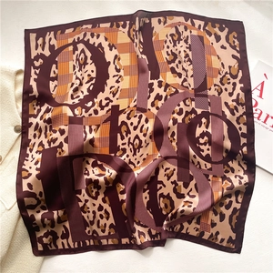Detailed macro view of soft leopard print silk scarf texture and abstract letter pattern