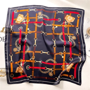Navy blue silk square scarf with golden chain and belt pattern in a flat lay view