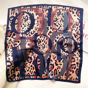Close-up of leopard print silk scarf with luxury monogram pattern and rolled edges