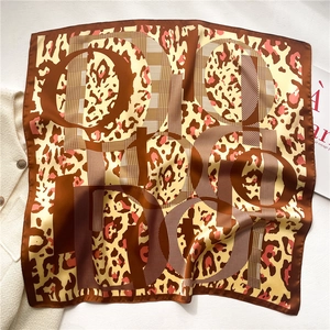 Detail view of leopard print silk scarf with classic brown patterns and luxury lettering